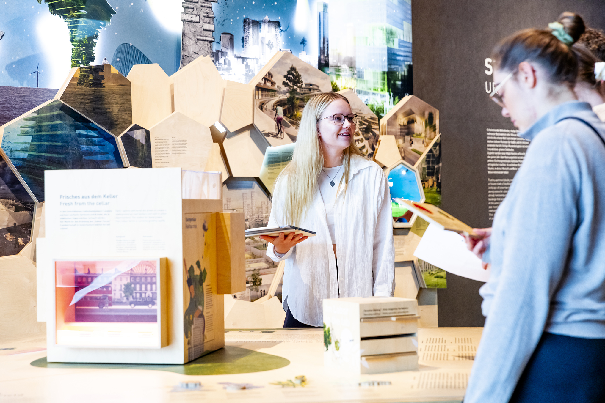 Zwei Frauen stehen vor einem Ausstellungstück und halten ein Tablet in der Hand.